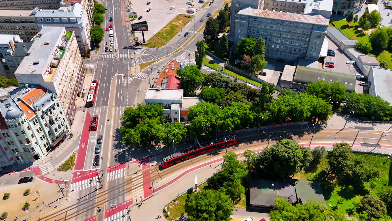 Red tram leaves the Old Bridge and moves to the old part of the city. Drone footage above sunny Bratislava, Slovakia.