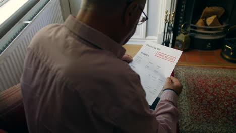 a lonely senior man opening a debt letter