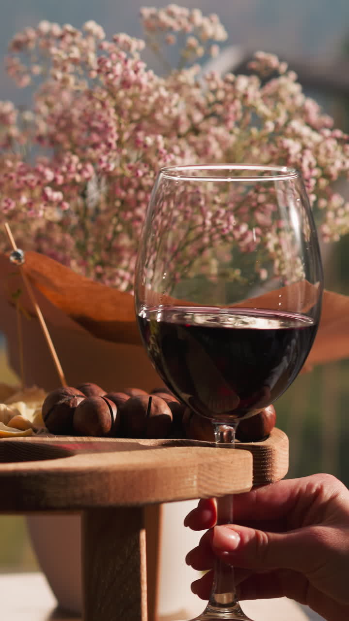 Couple clinks glasses of wine in restaurant closeup. Man and woman take goblets of delicious red alcoholic drink from wooden snack tray at date