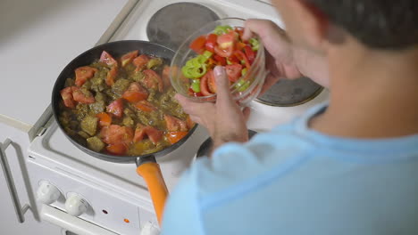 hombre añadiendo pimienta fresca a la sartén