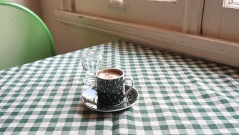 turkish coffee and water on a green checked tablecloth