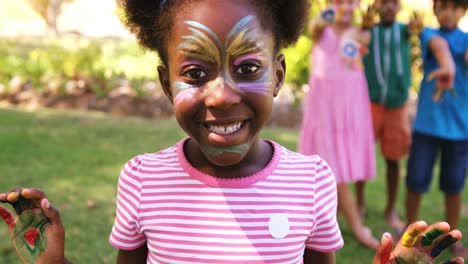 girl with painted face and hands in park