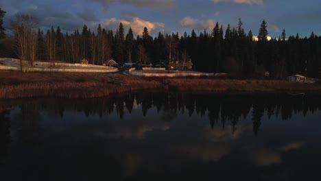 Hermosa-Toma-De-Enfoque-Sobre-El-Lago-De-Vislumbre-En-Columbia-Británica,-Canadá,-Hermosos-Reflejos-Del-Cielo-En-El-Agua,-Luz-De-La-Hora-Dorada,-Bosque-De-Abetos,-Rancho-Casero