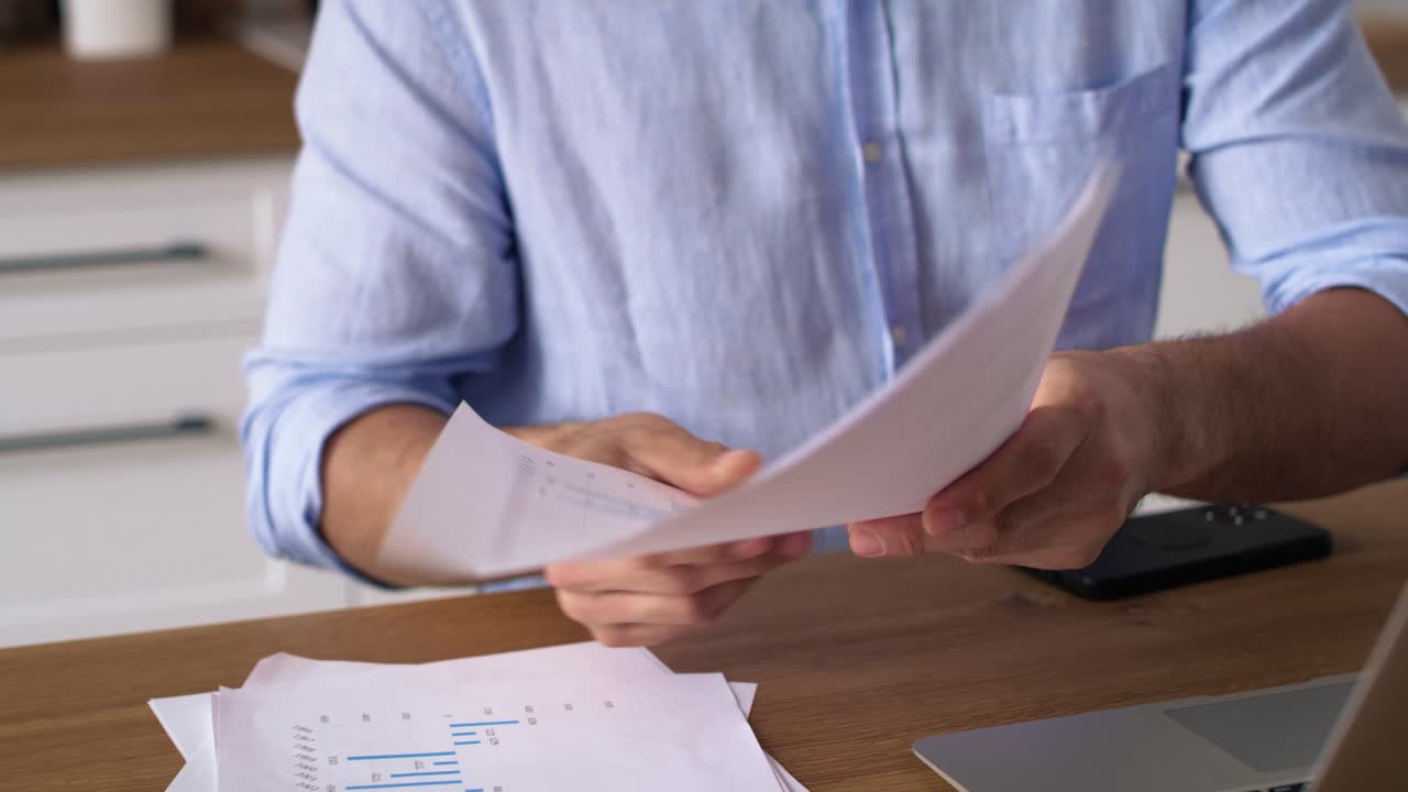 video de seguimiento de un hombre analizando documentos mientras trabaja desde casa