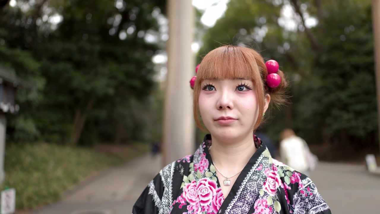 Una donna che indossa un kimono floreale sta davanti a un portale di santuario shintoista a Tokyo, Giappone