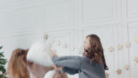 Closeup-mom-and-daughter-throwing-pillows-on-bed-in-in-luxury-bedroom.