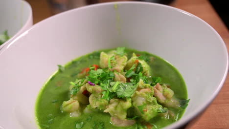 Delicioso-Estofado-De-Marisco-Peruano-Con-Caldo-De-Cilantro-Servido-En-Un-Tazón-Blanco---Primer-Plano,-Tiro-Lento-En-órbita