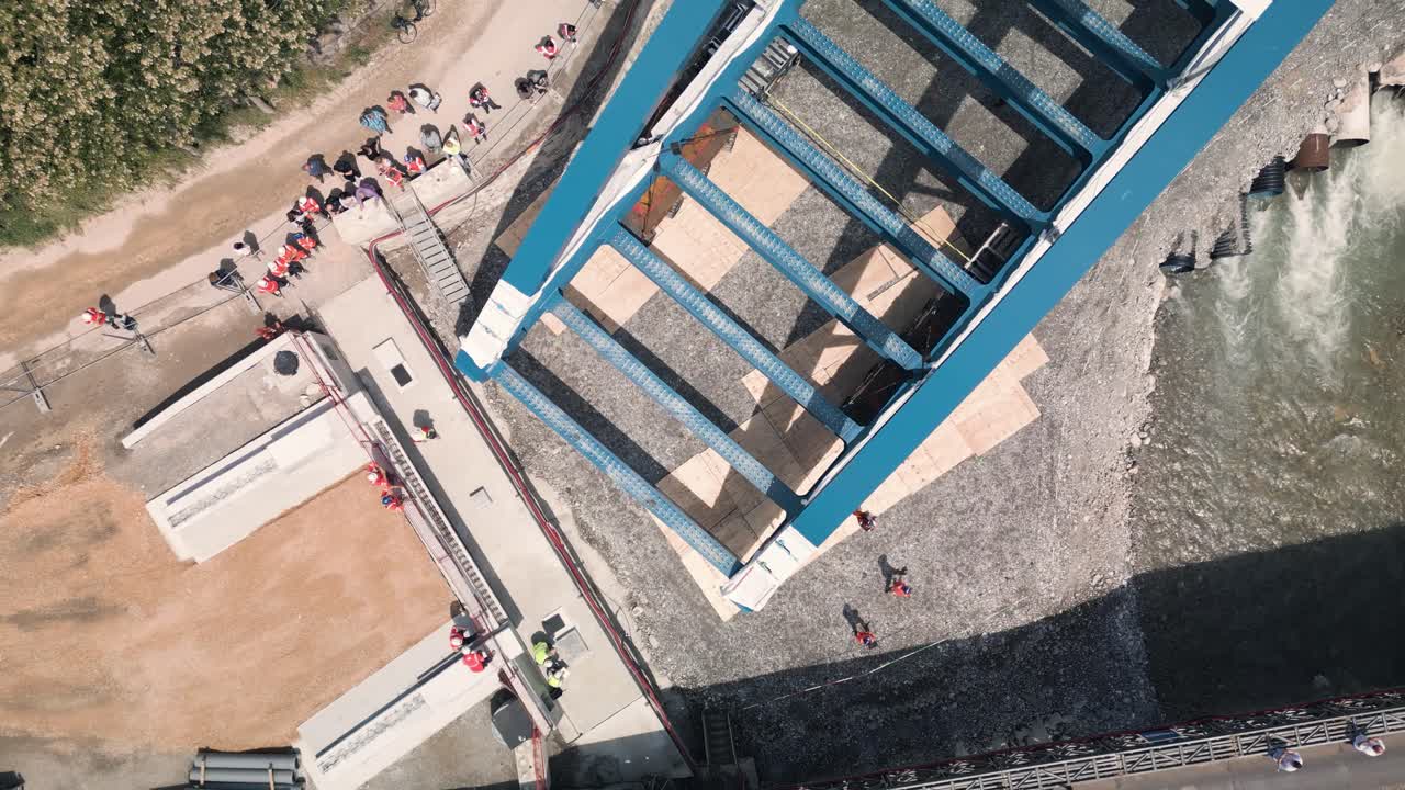 Workers rigging large bridge structure at construction site near river in Tende, South of France