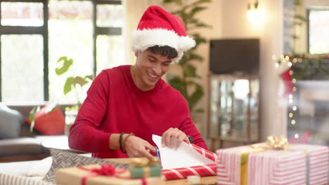 biracial man wrapping christmas present in decorative paper, slow motion