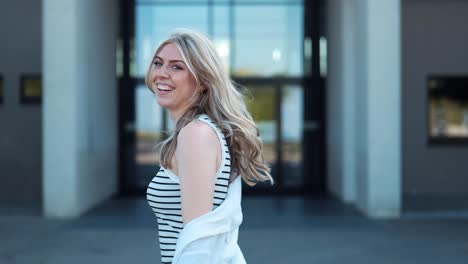 beautiful young tall woman running towards modern building and smiling at camera