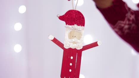 someone holding a figure of santa claus made with popsicle sticks