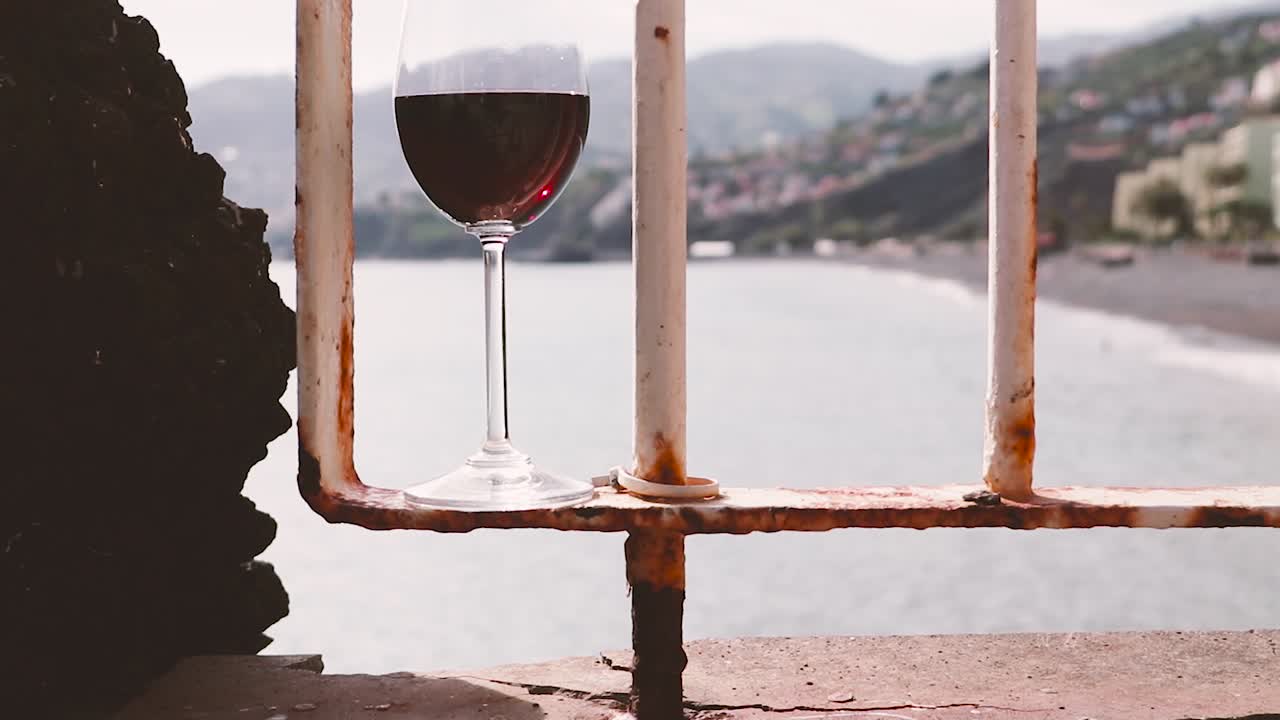 una copa de vino tinto en la terraza con vistas a la costa y las montañas de madeira