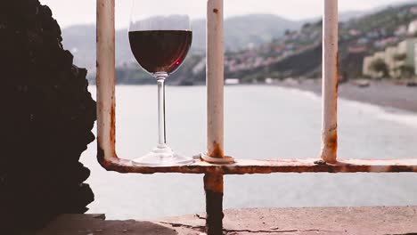 glass of red wine on terrace railing overlooking madeiran coastline and mountains