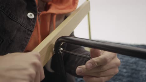 Close-up-of-a-man's-hand-tightening-screws-on-a-chair