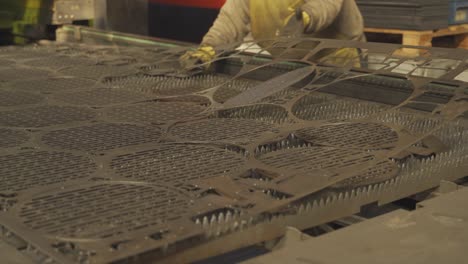 close up shot of industrial worker taking pieces of flat sheet metal at factory