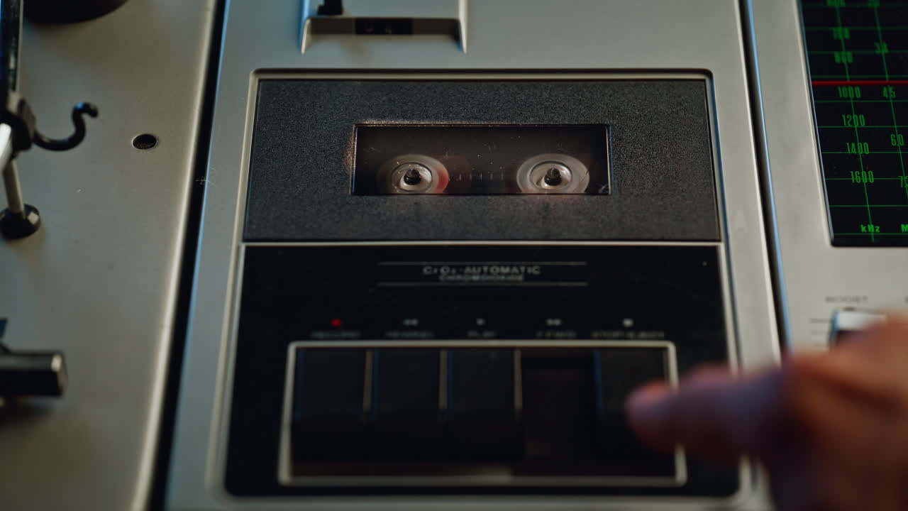 Hands pressing rewind button on old sound recorder closeup. Unrecognizable man