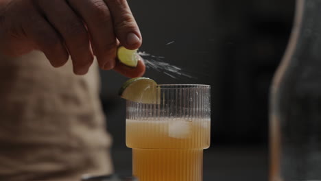 young male squeezing lime or lemon over fresh mixed cocktail in a drinking glas  4k slow motion close up