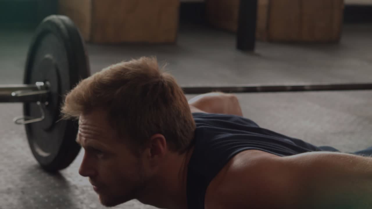 Man doing dumbbell pushups in gym, lowering chest and starting HUD marking hands chest for strength