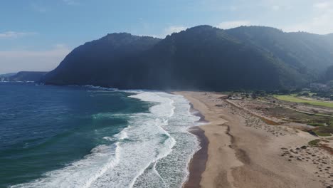 aerial view of playa grande showing waves crashing on the coastline in quintay, chile. dolly left