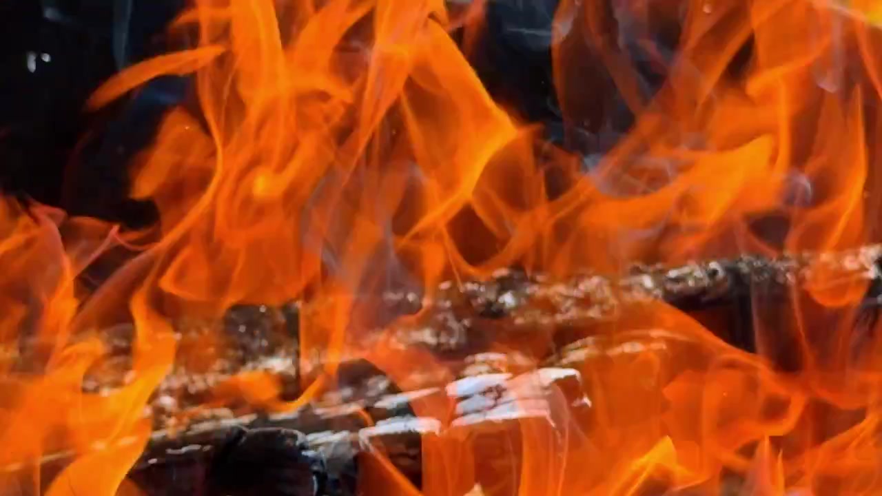 Aktive orange flammer over brændende trækul. Makrobillede af intens varme og røg fra bålbrænde
