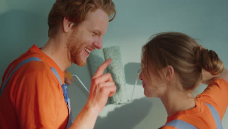 happy couple painting wall together indoors. family meeting by rollers on wall.