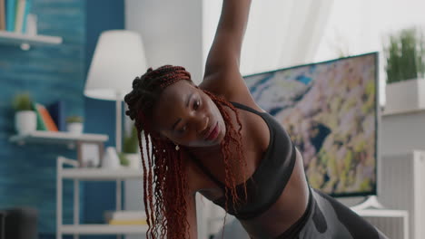 athlete black woman training on yoga map in living room standing in side plank