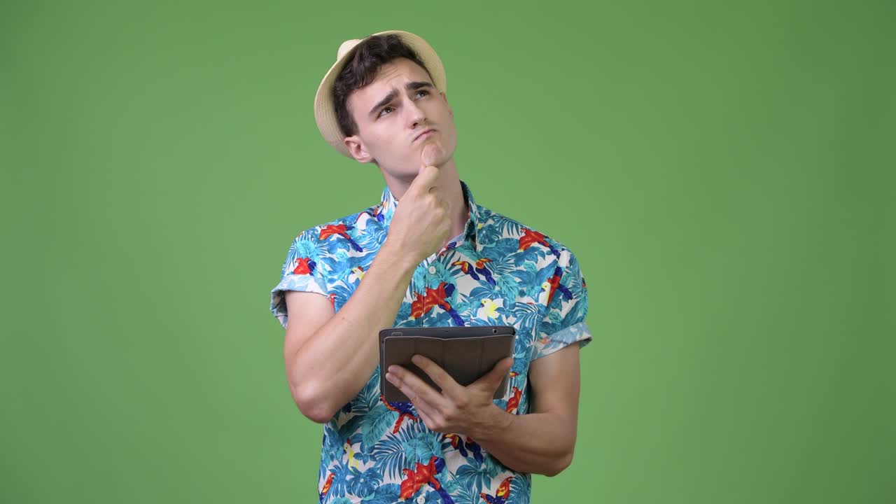 Young handsome tourist man thinking while using digital tablet