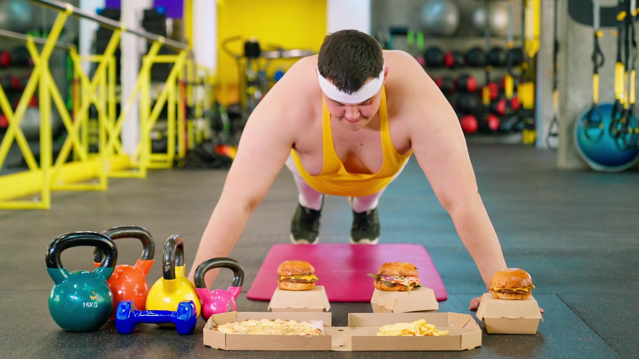 Uomo in sovrappeso che fa flessioni in palestra, tentato dal fast food