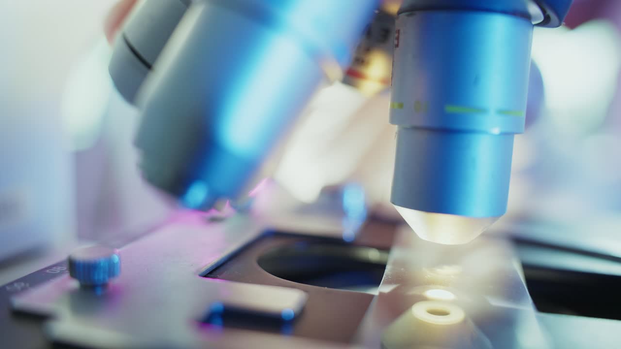 Close-up of Microscope Objective Lens Adjustment in Laboratory
