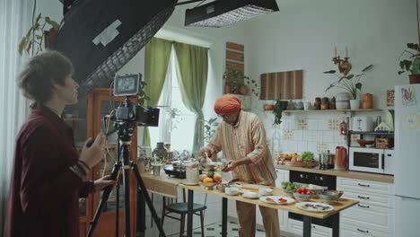 female filmmaker recording indian chef in kitchen with camera setup