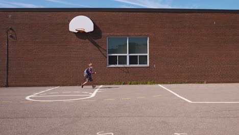 Little-boy-in-a-face-mask-runs-across-a-school-yard