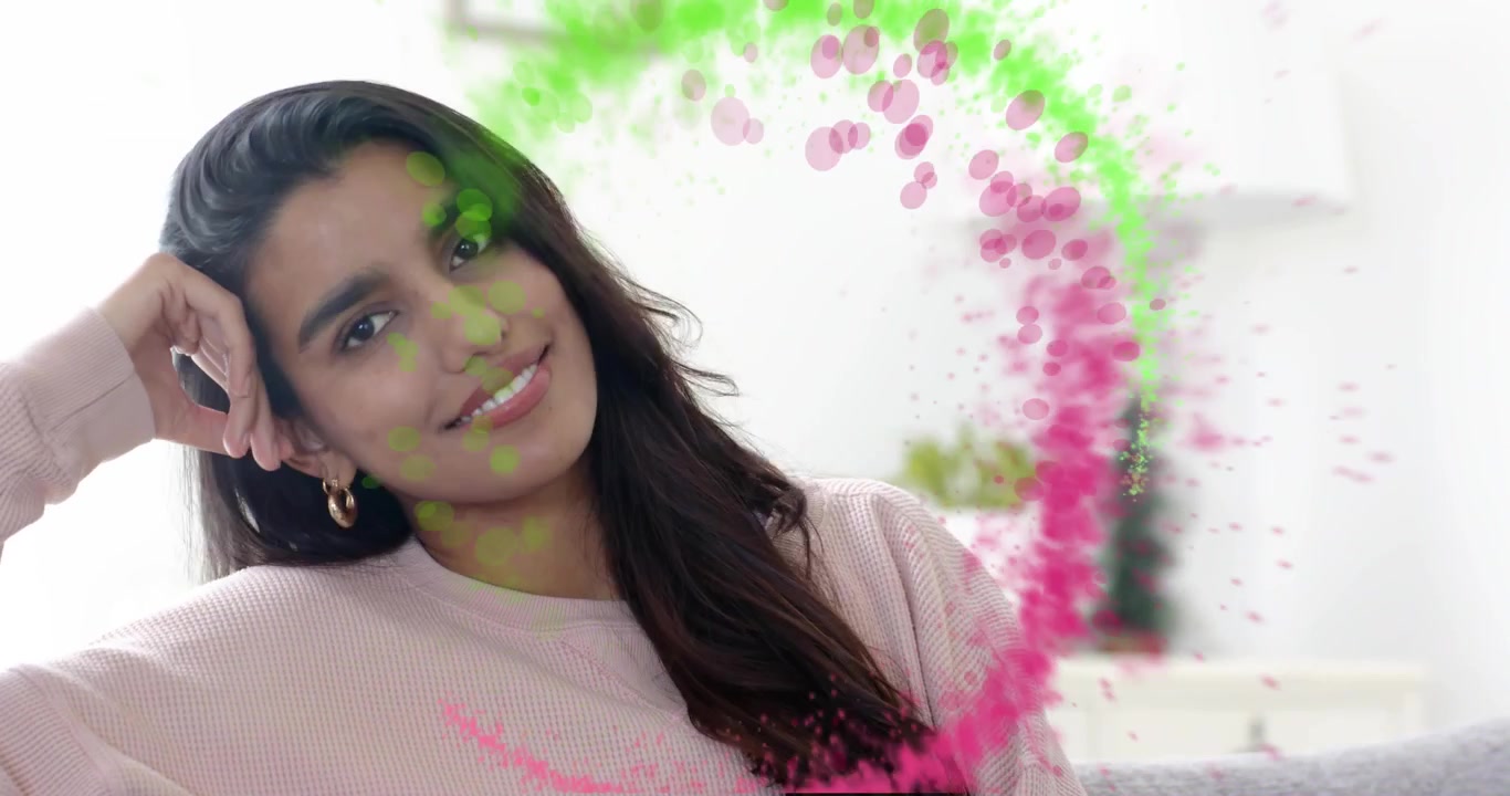 Woman sitting sofa receiving swirling green-pink particle ring demonstrating tech visualization