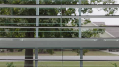 Looking-outside-in-between-blinds-while-car-passes