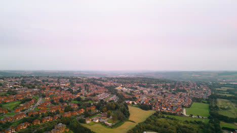 Drone-footage-showcases-the-fame-of-Dewsbury-Moore-Council-estate,-a-renowned-UK-urban-housing-complex,-red-brick-terraced-homes,-and-the-industrial-Yorkshire-landscape-on-a-summer-evening