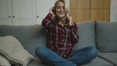 mujer con auriculares divirtiéndose en el sofá