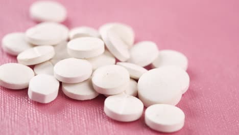 white round pills on pink background