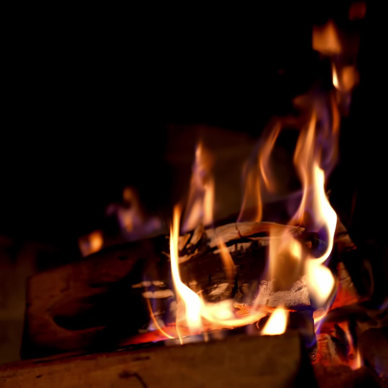 Wooden logs burning in vivid flame in dark. Burning fire in fireplace. Warm fire flames in a country house. Home hearth. Close-up
