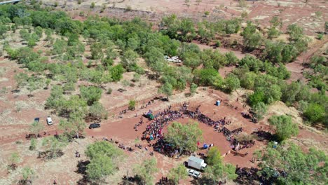 Vista-Aérea-Levantando-Y-Saliendo-De-La-Ceremonia-Al-Comienzo-Del-Festival-Del-Día-De-La-Libertad-Y-La-Comunidad-De-Kalkaringi-En-El-Fondo,-Territorio-Del-Norte,-Australia