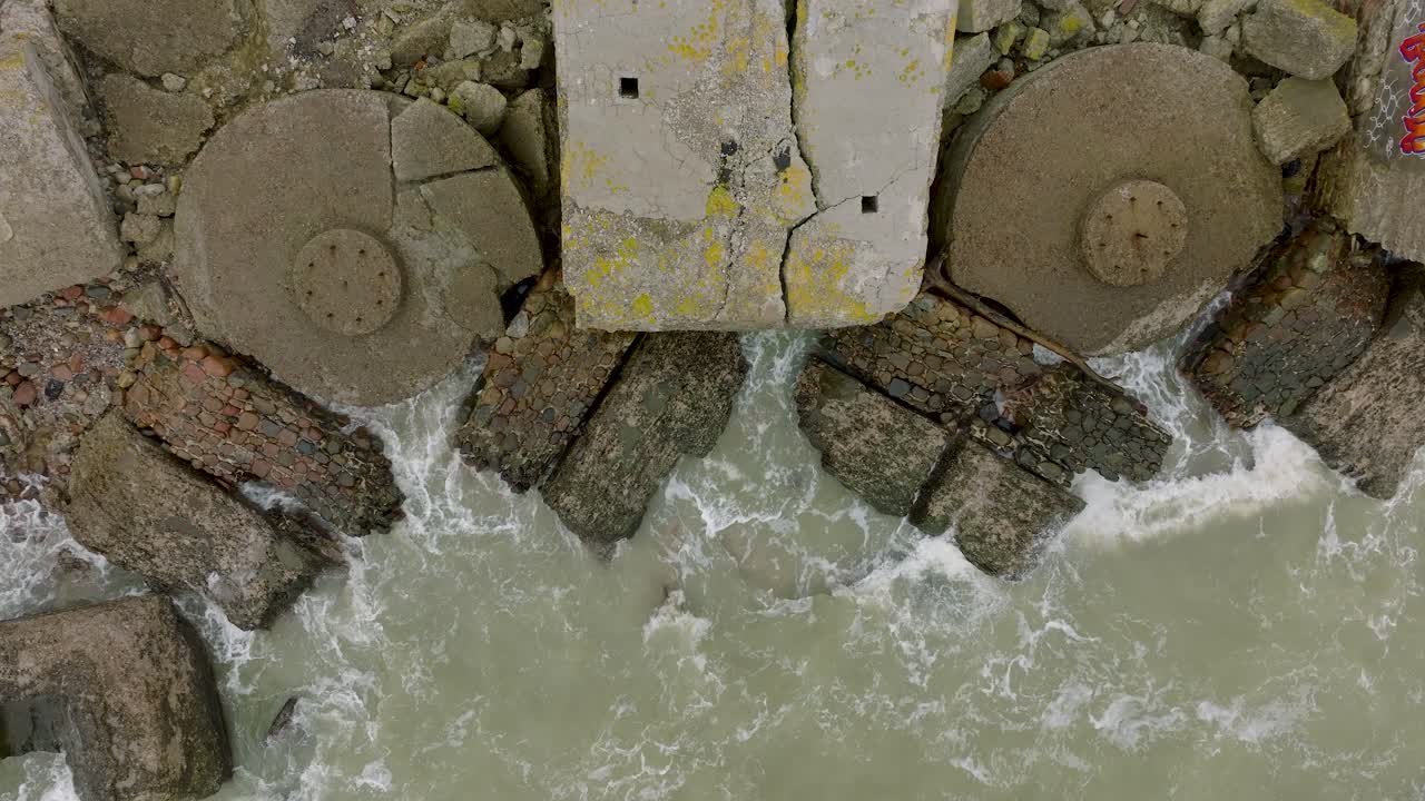 vista aérea de pájaros de edificios de fortificación costeros abandonados en los fuertes del norte de karosta, costa del mar báltico, grandes olas, día nublado, cámara lenta, tiro ascendente de drones