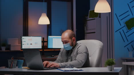 hombre de negocios sobrecargado de trabajo con máscara facial contra covid-19 trabajando en una oficina de puesta en marcha