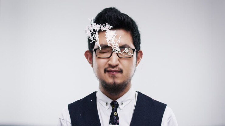 Uomo asiatico divertente con il viso ricoperto di stelle filanti spray in slow motion, serie di foto da cabina fotografica per matrimonio