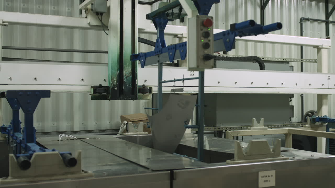 Slider shot of machine lowering metal parts into a chemical bath for treatment in a manufacturing facility