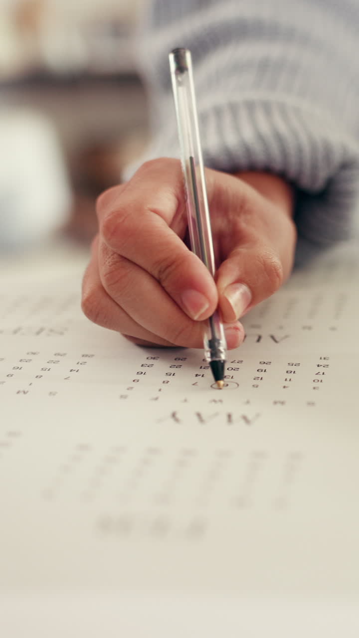 Nærbillede af en hånd, der markerer en dato i en kalender med en pen