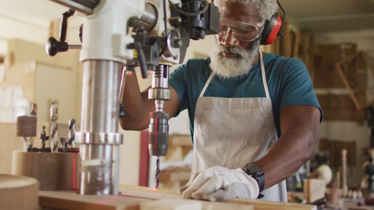 carpintero afroamericano perforando madera con un taladro láser en un taller de carpintería