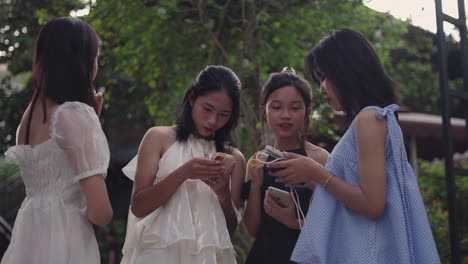 four friends using smartphones outdoors