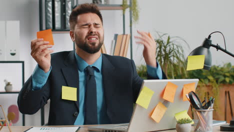 hombre de negocios cansado, triste y agotado trabajando en una computadora portátil en la oficina con muchas tareas adhesivas, ataque de pánico