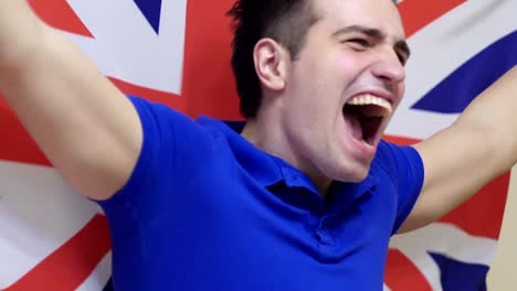 british young man celebrating while holding the british flag in slow motion