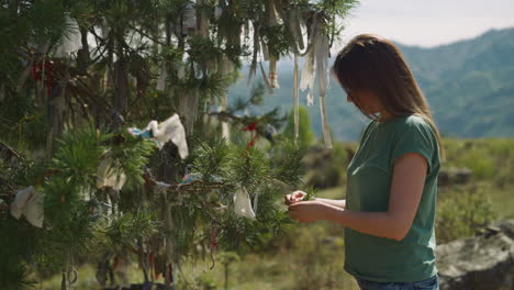 lady ties bow to make wishes on spruce tree twig at country