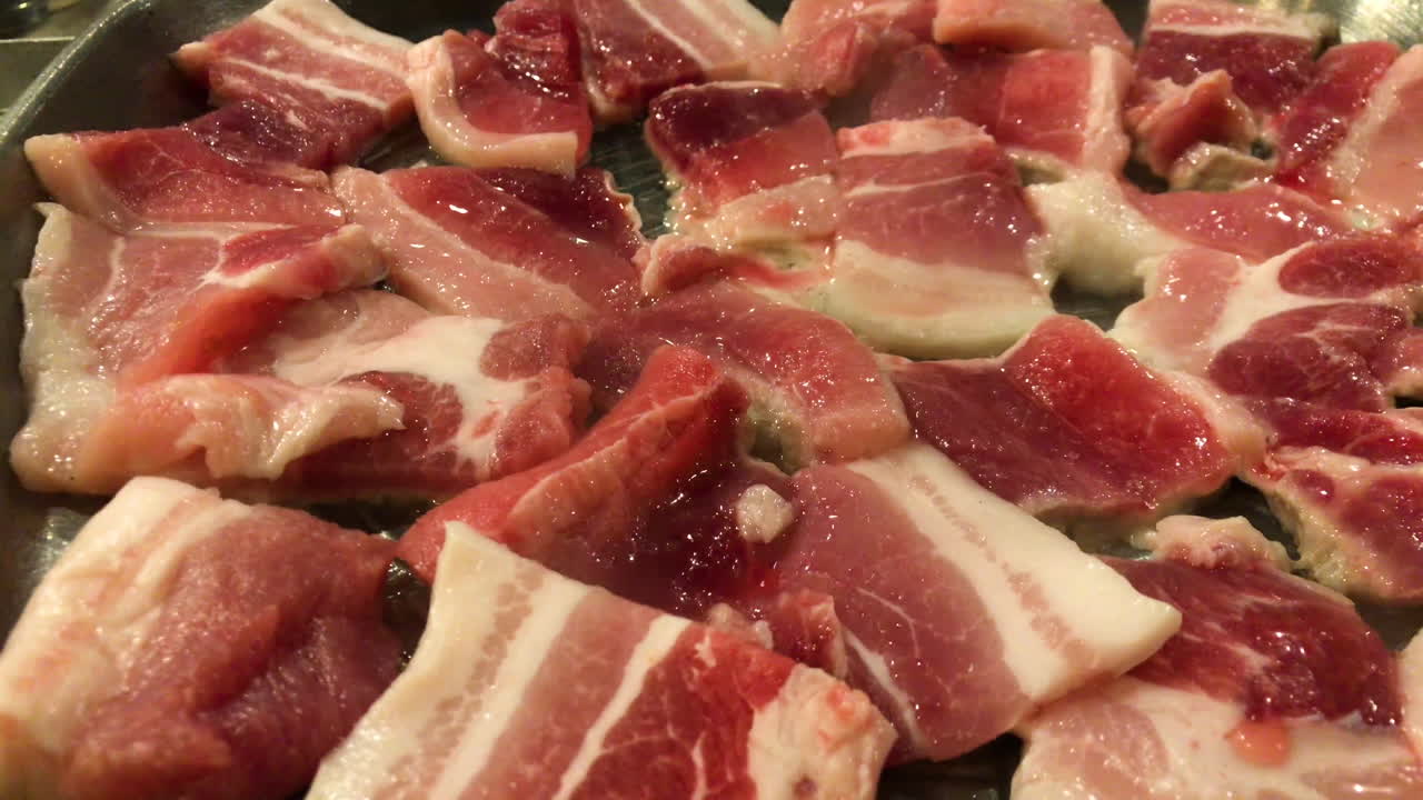 맛있는 김이 나는 뜨거운 삼겹살이 한식당의 핫플레이트 그릴에서 구워지고 있습니다.