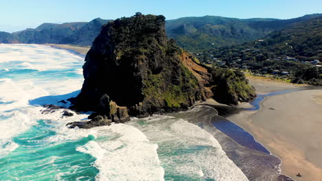 Beautiful-aerial-reveal-around-Lion-Rock-on-Piha-Beach,-New-Zealand-landscape